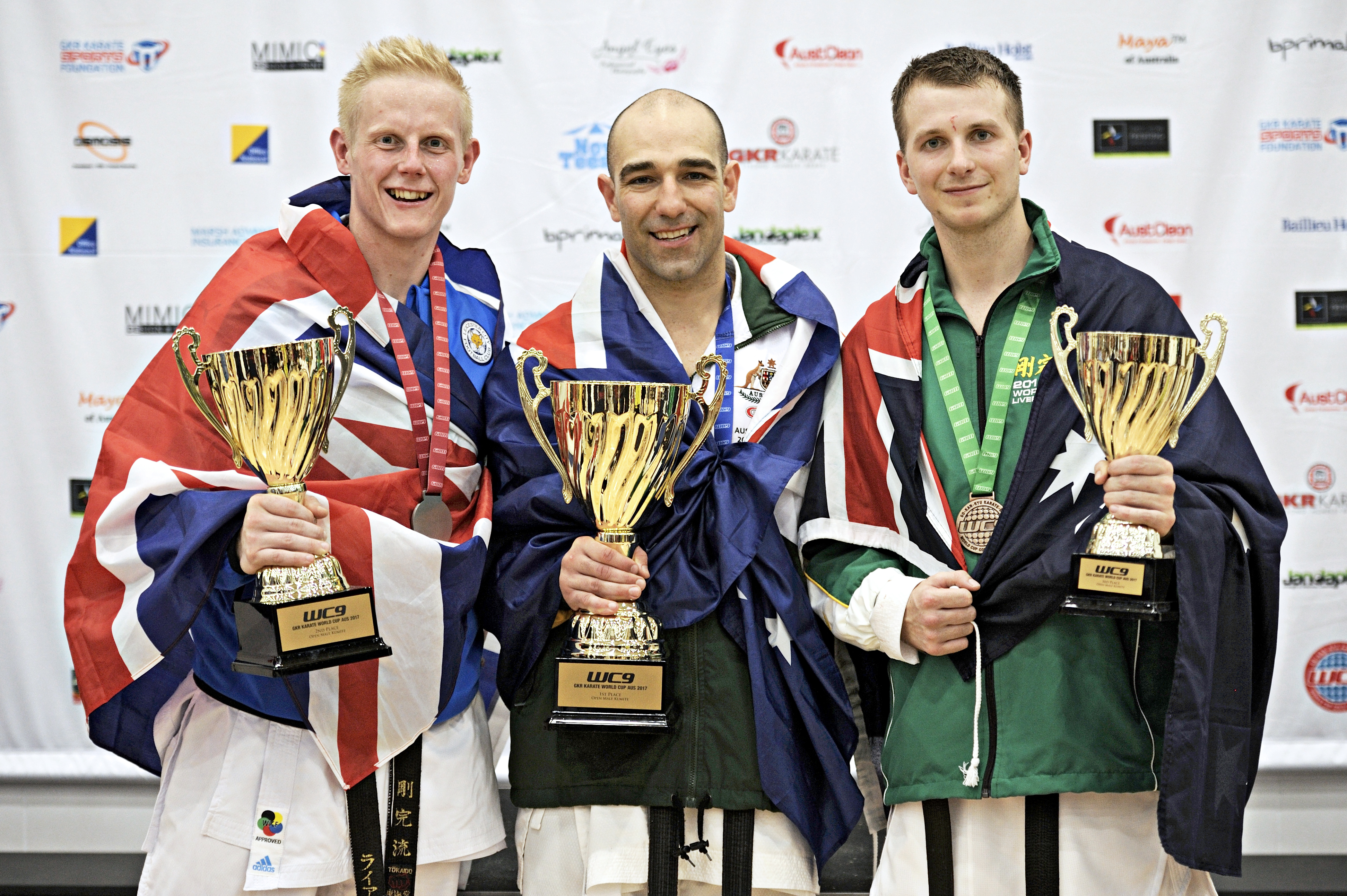three men wearing there country flags, showing off their trophies three men wearing there country flags, showing off their trophies